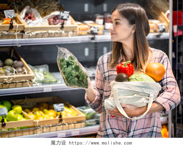 挑选蔬菜的女人一个年轻的女孩在商店里选择水果和蔬菜，把